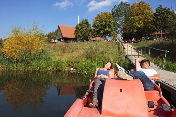 Ruhen auf dem Tretboot in Gern Eine Frau und ein Mann liegen auf einem Tretboot an einem Steg im Altmühlüberleiter. Der steg führt durch eine grüne Böschung hianuf zum Kiosk in Gern.