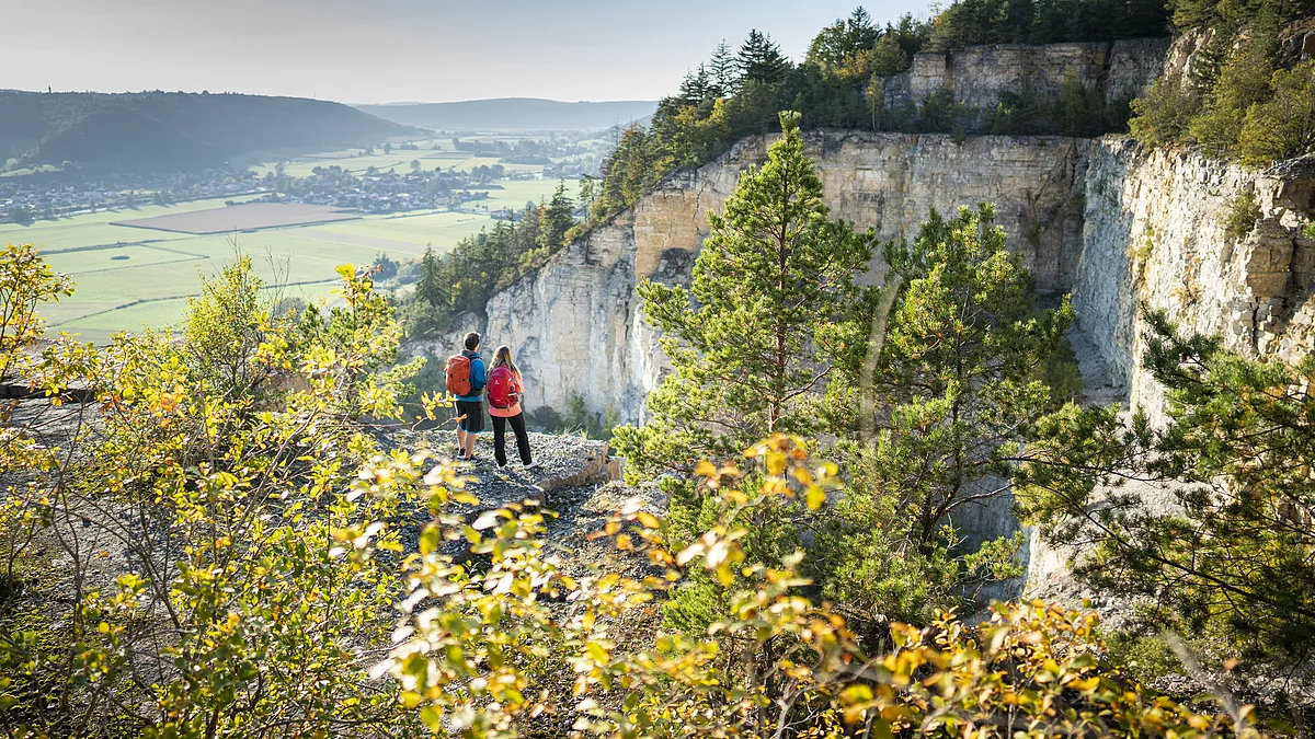 Geotop am Arzberg bei Beilngries Zwei Personen mit Rucksäcken stehen auf einem Felsvorsprung und blicken ins Tal.